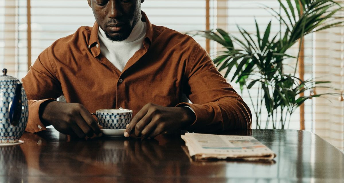 Un homme prend une pause autour d'une tasse de thé à une table en bois